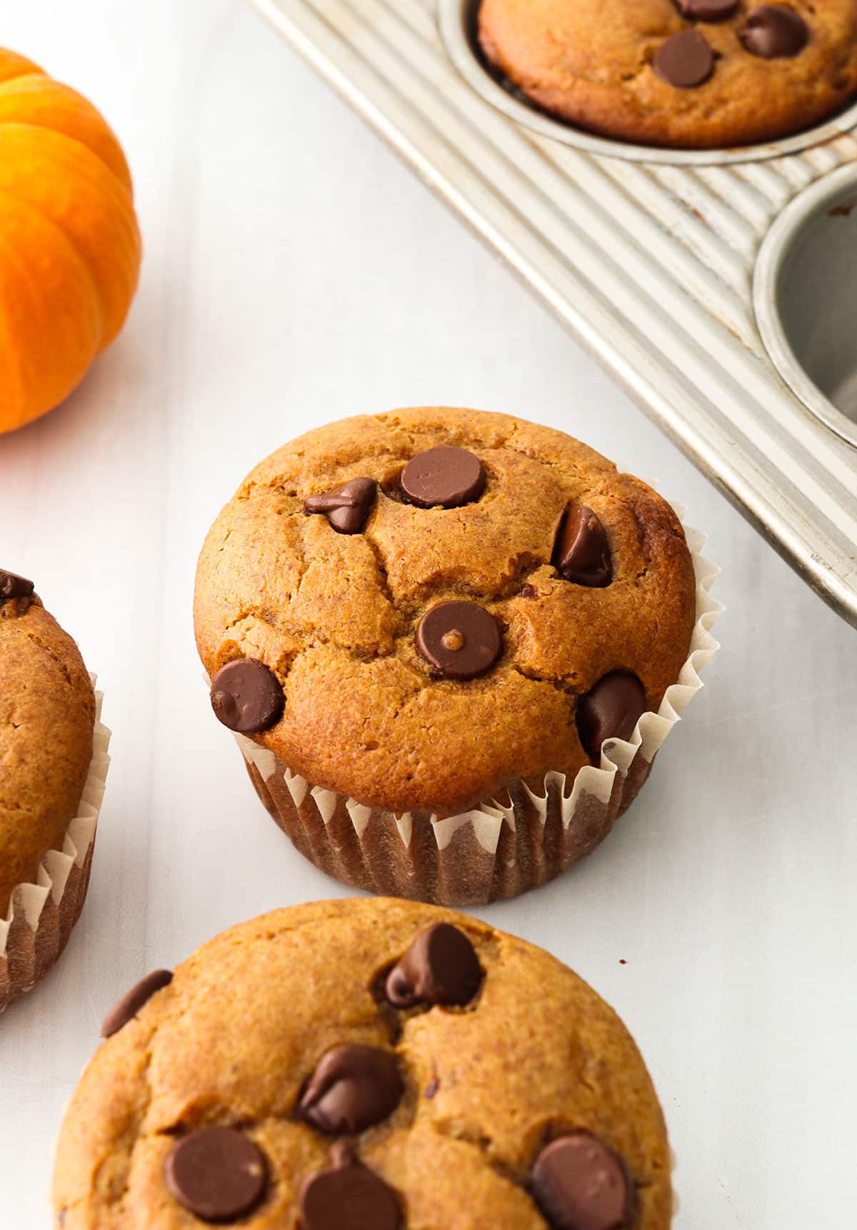 paleo pumpkin muffins cooling on a white surface.