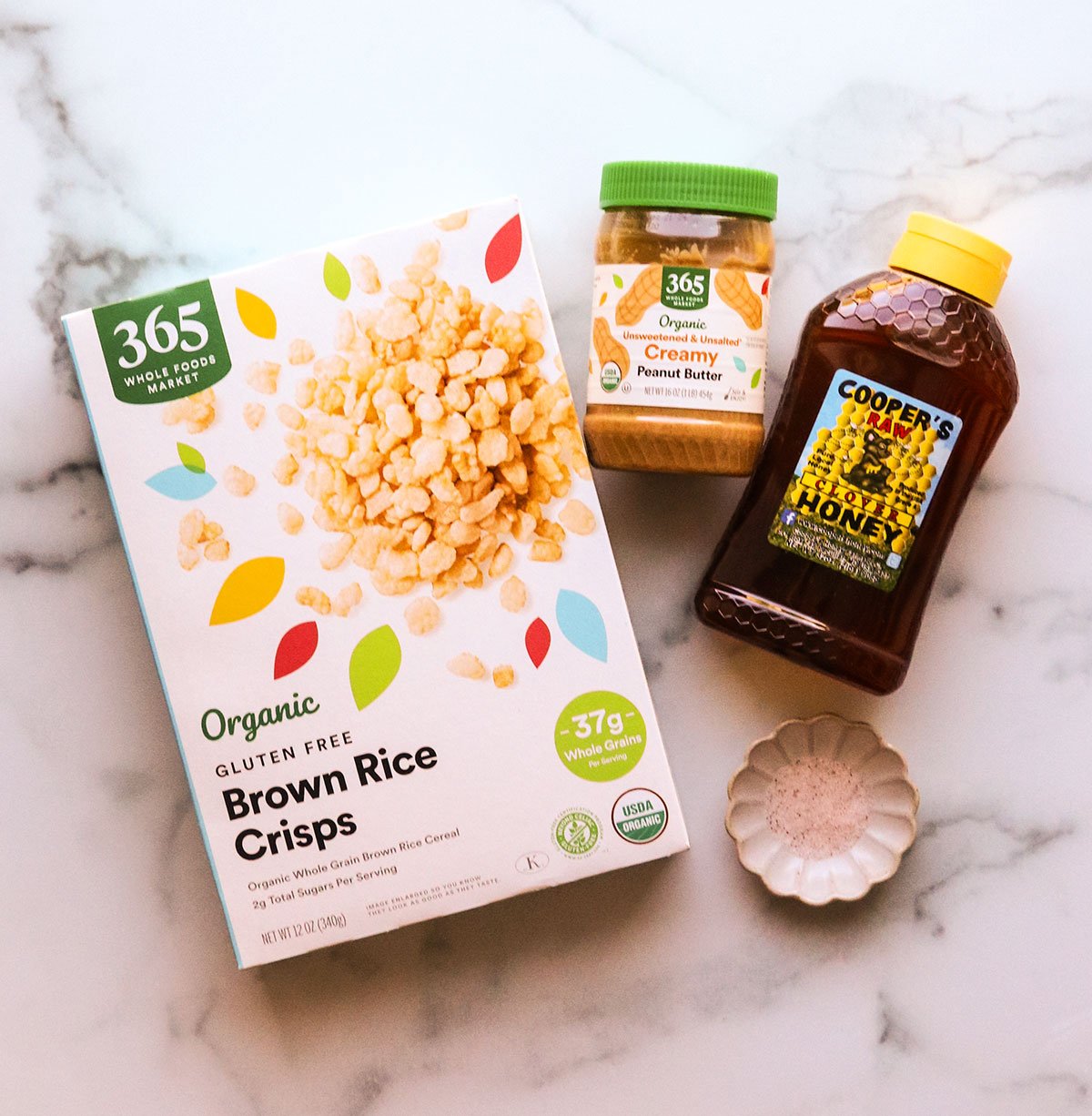 crispy rice cereal sitting near peanut butter and honey on a marble surface.