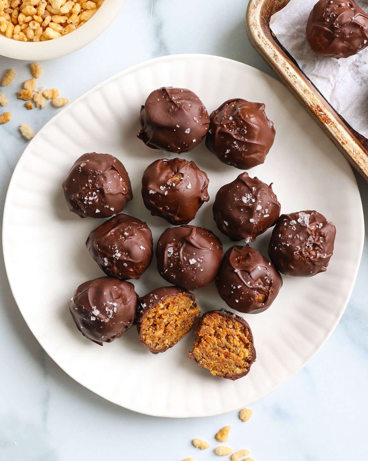 chocolate covered peanut butter balls on a white plate with one cut in half. 