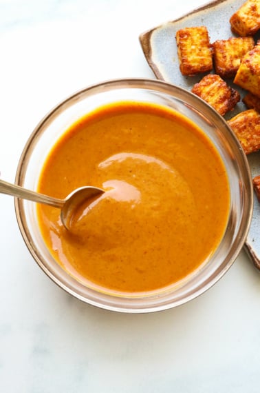 peanut sauce stirred in a glass bowl with a spoon.