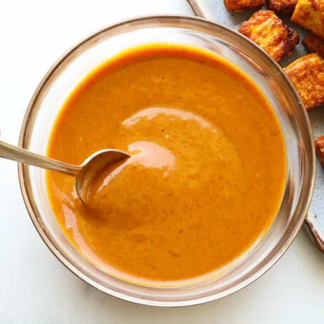 peanut sauce stirred in a glass bowl with a spoon.