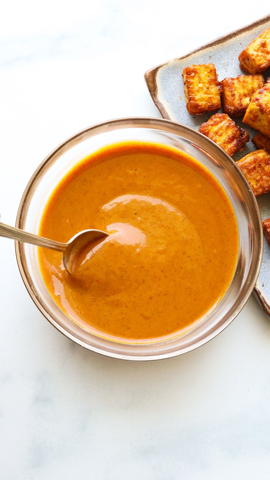 peanut sauce stirred in a glass bowl with a spoon.