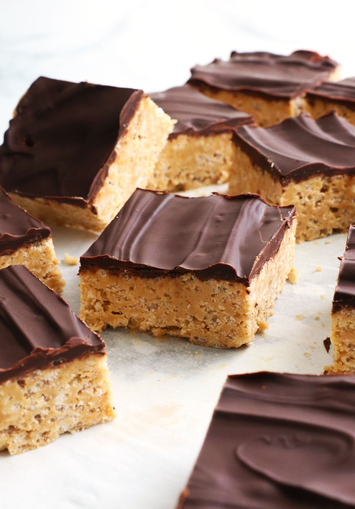 protein rice crispy square topped with a chocolate coating on parchment paper. 