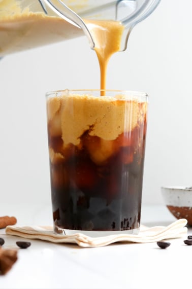 pumpkin creamer poured from a blender on top of iced coffee