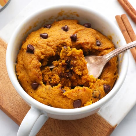 pumpkin mug cake with a fork inside the white mug.