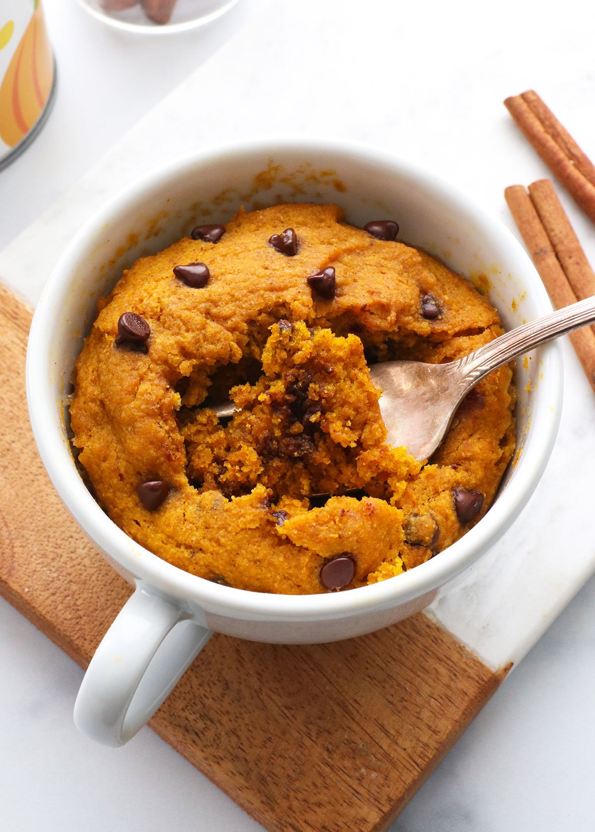 pumpkin mug cake with a fork inside the white mug.