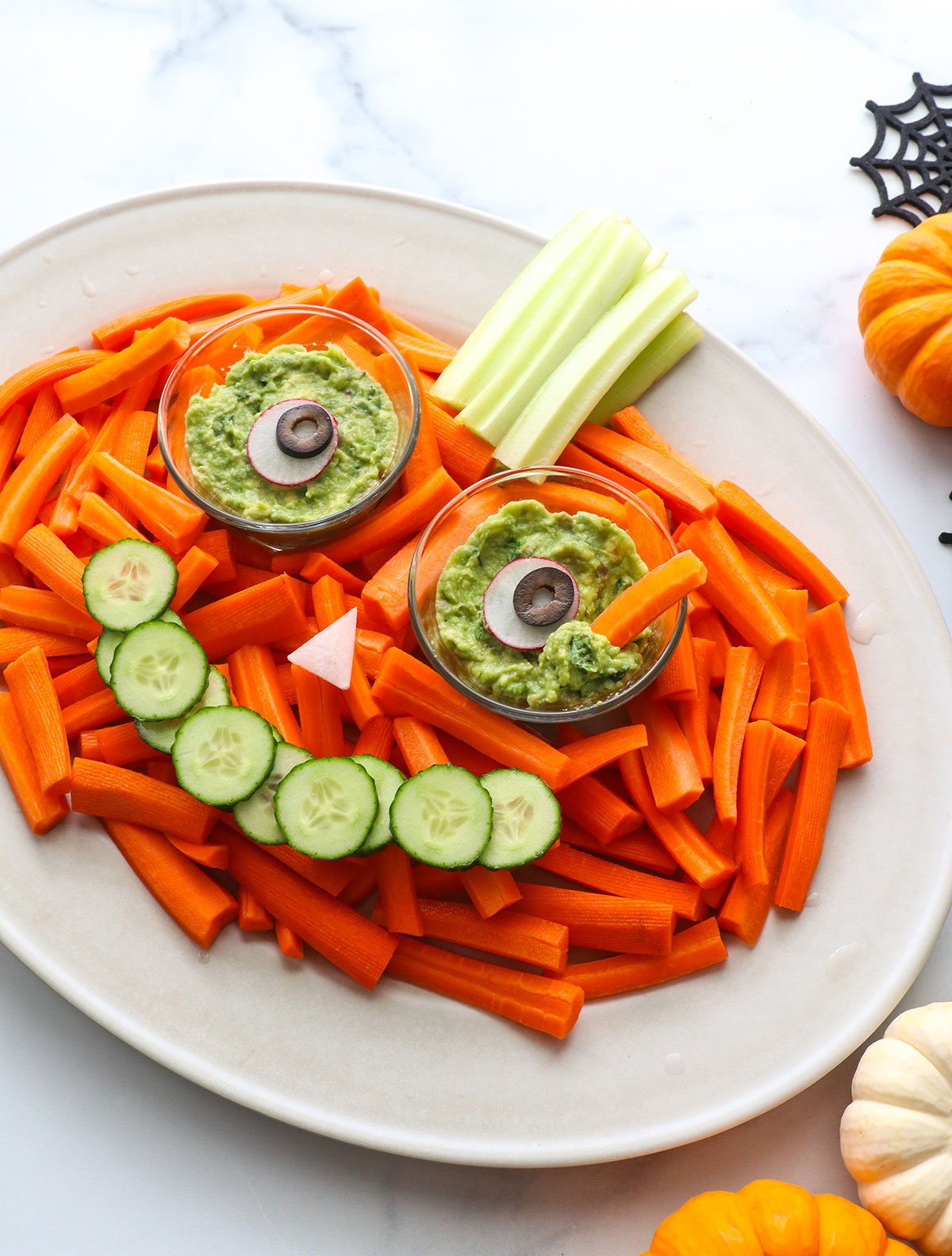 veggies arranged on a platter to look like a pumpkin with eyes and smile.