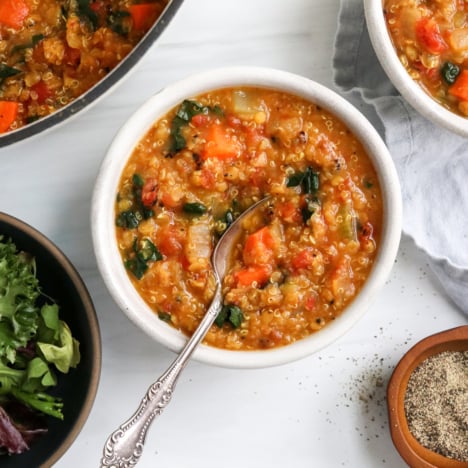 Quinoa soup in a white bowl with a spoon inside