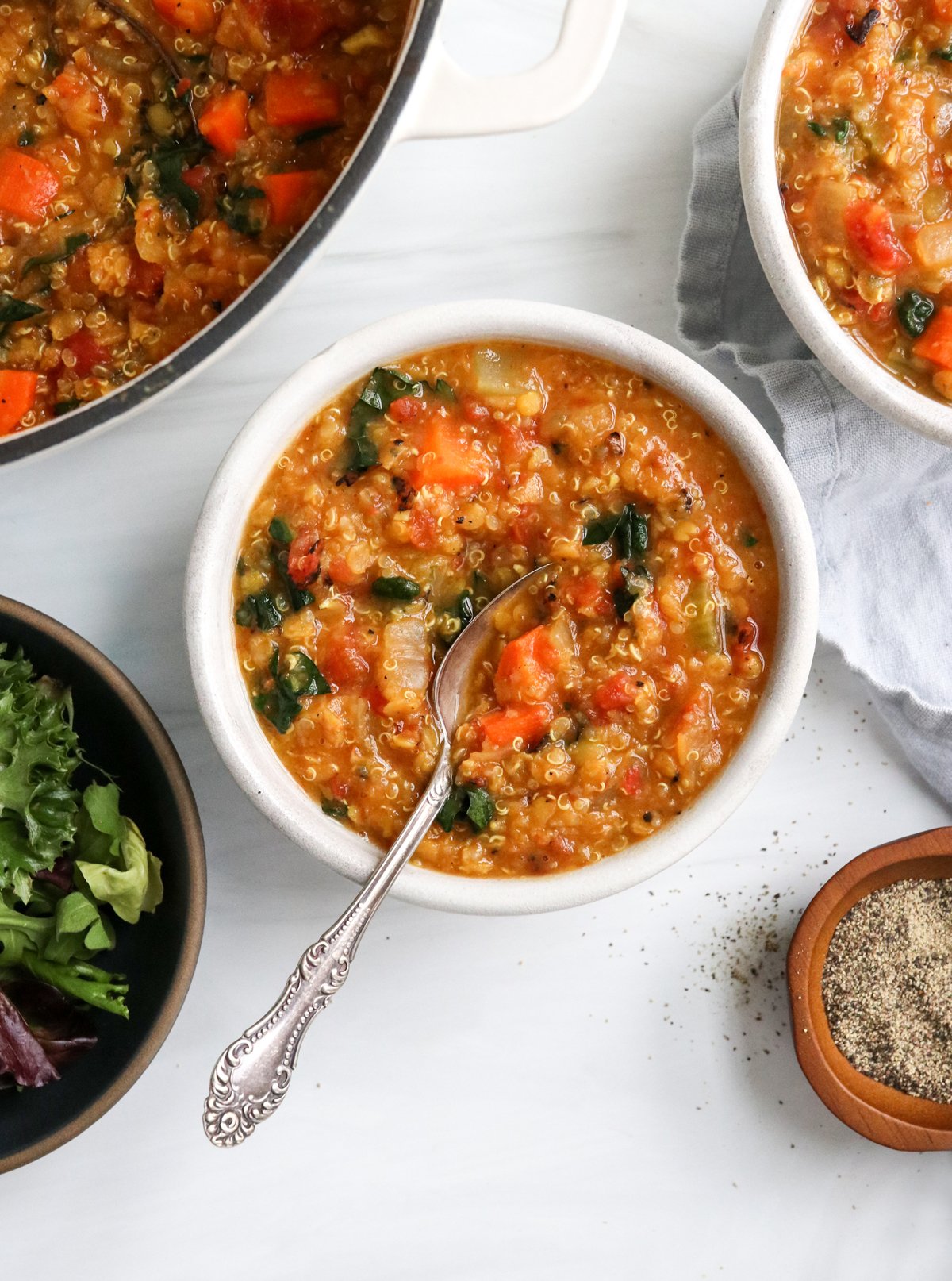 Quinoa soup in a white bowl with a spoon inside