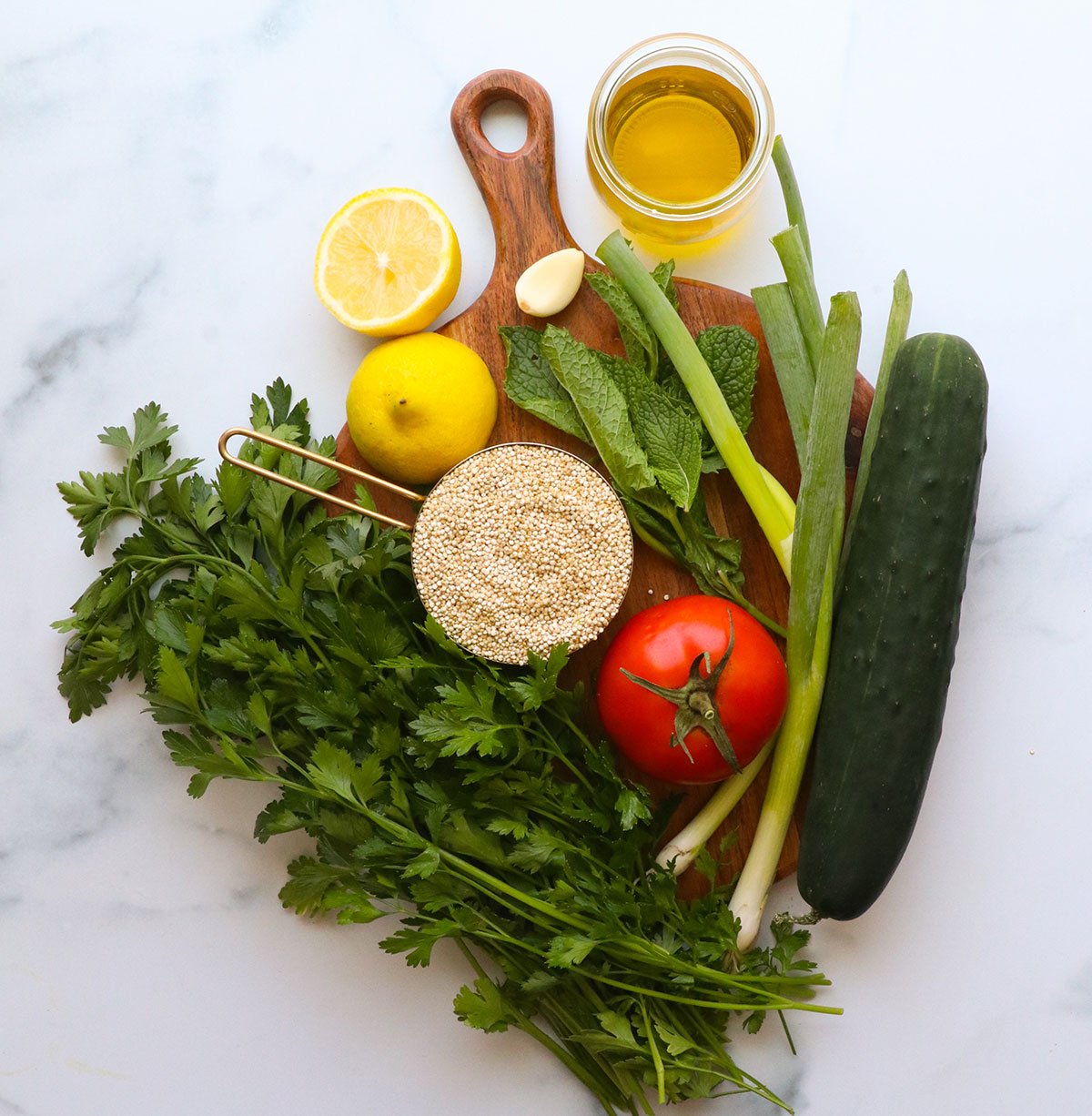 parsley, cucumber, mint, green onions, dry quinoa, and lemon on a board.