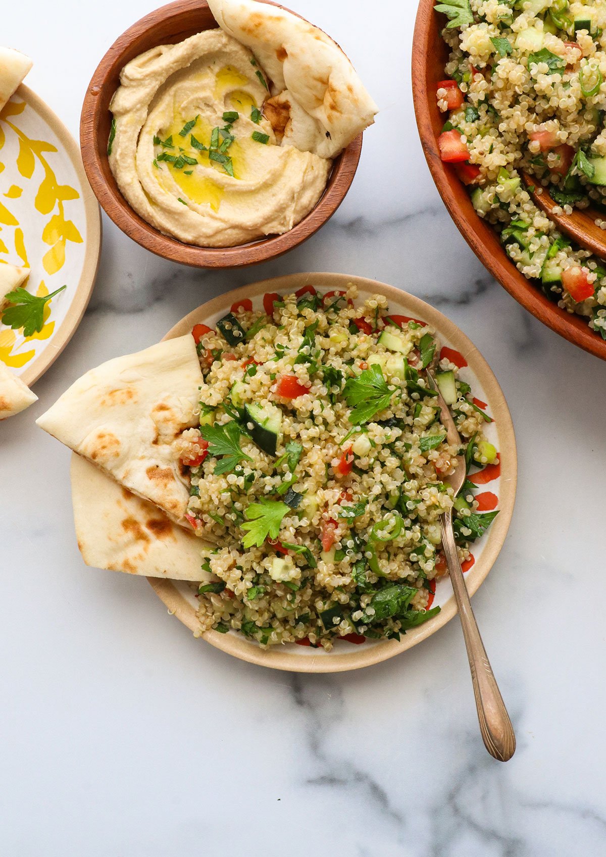 quinoa tabbouleh served on a plate with naan bread and hummus.