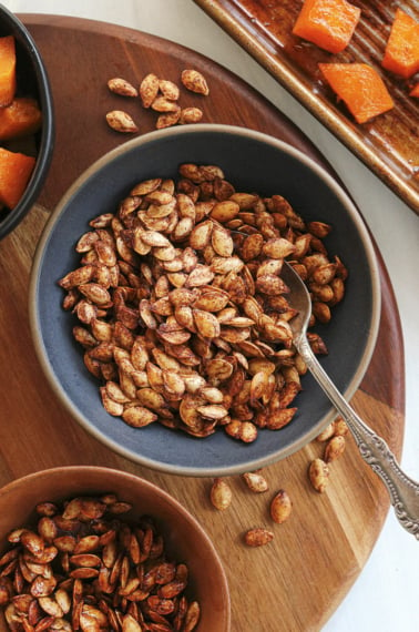 roasted squash seeds served in a bowl with spoon.