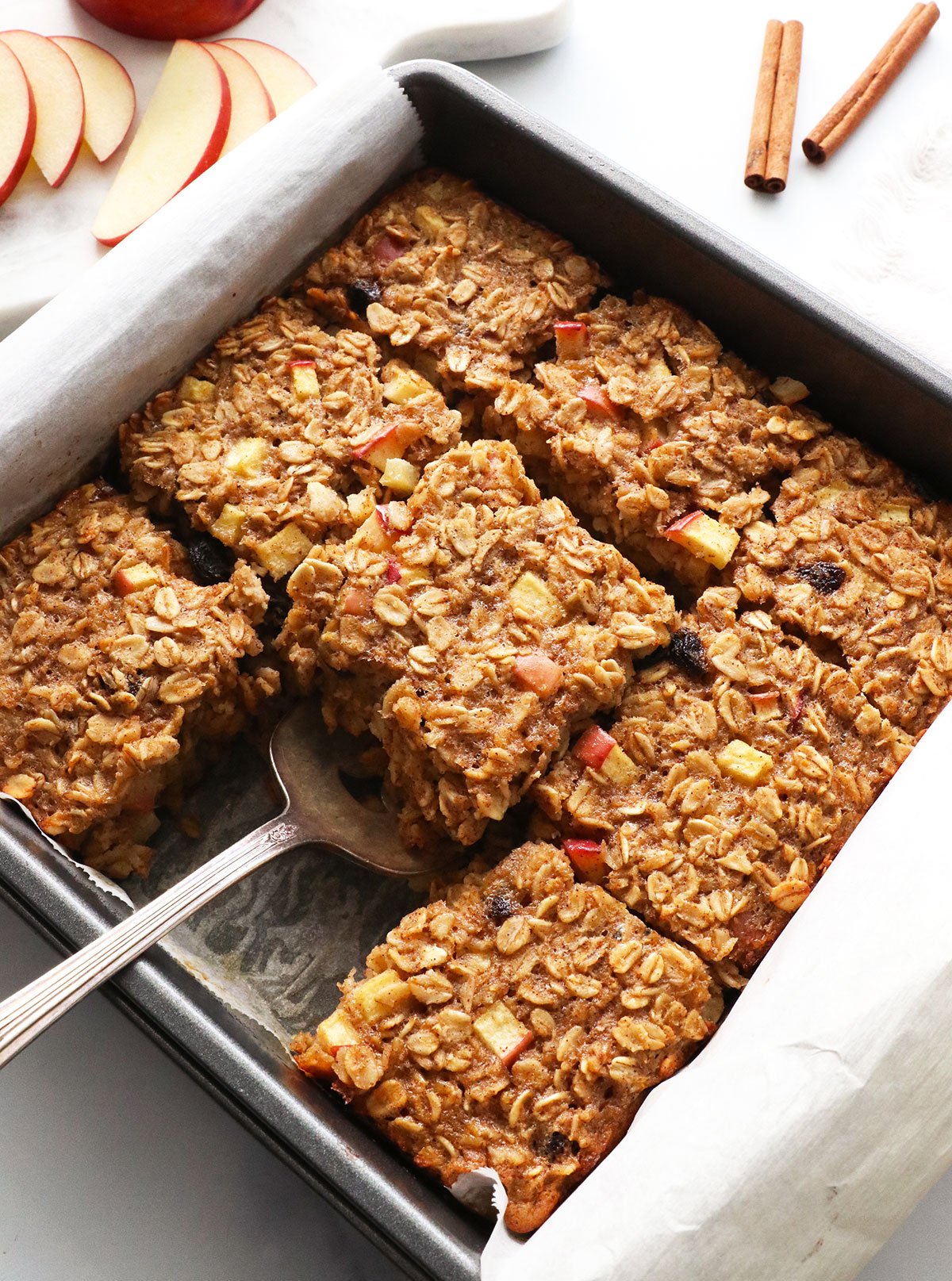 slice of apple baked oatmeal lifted out of the pan with a spatula.