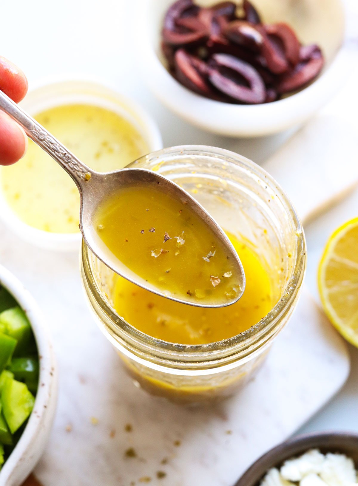 Greek dressing lifted on a spoon from the glass jar.