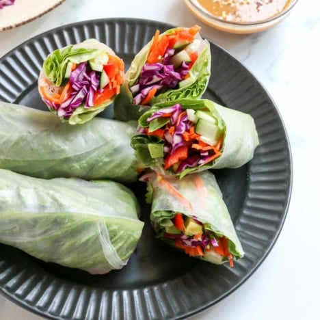 spring rolls on black plate with peanut sauce