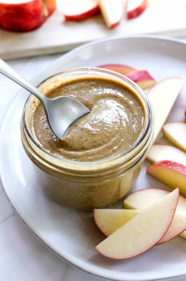 sunflower butter in a jar with a spoon lifting it up.