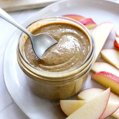 sunflower butter in a jar with a spoon lifting it up.