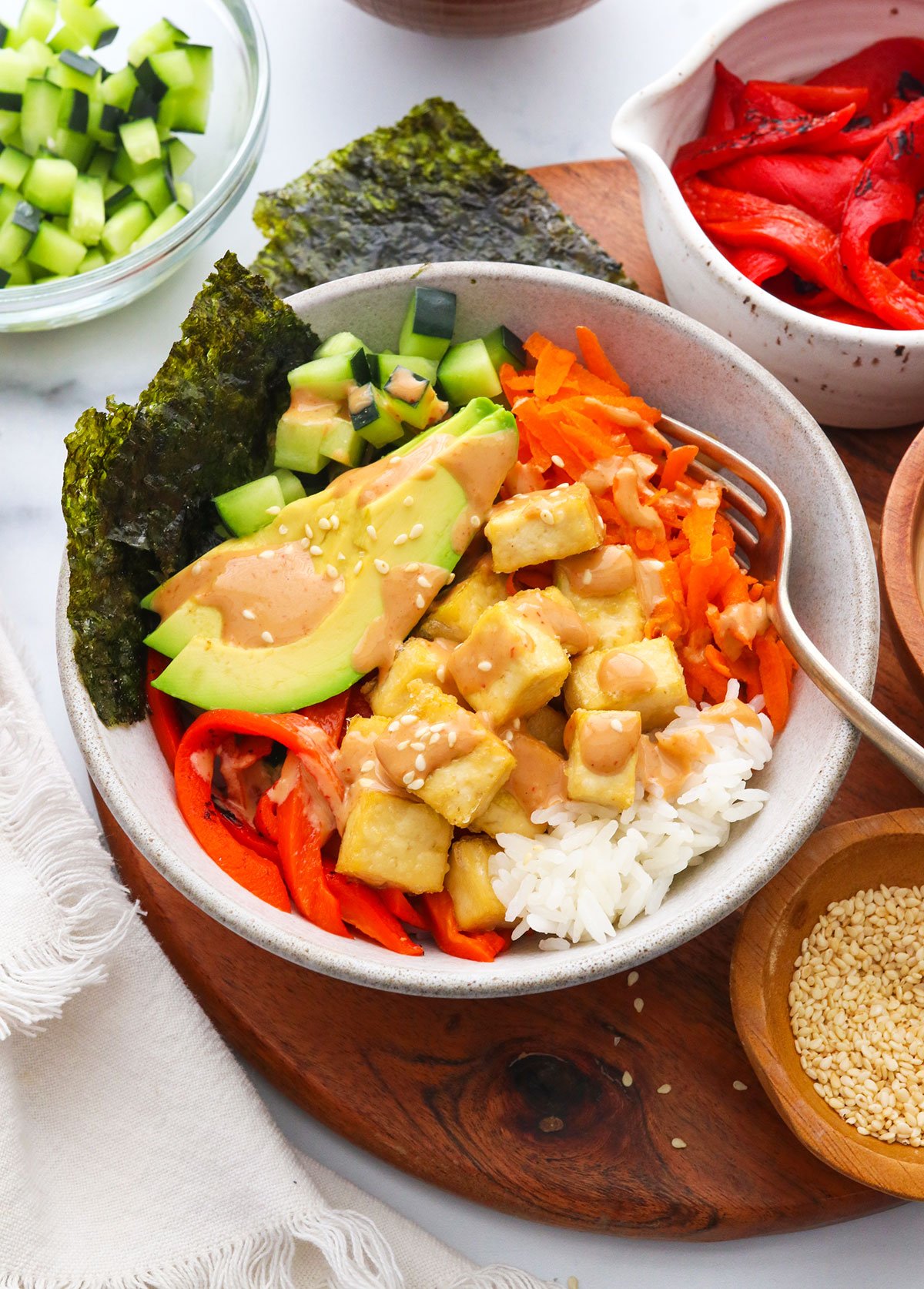 vegan sushi bowls topped with tofu and sriracha sauce.