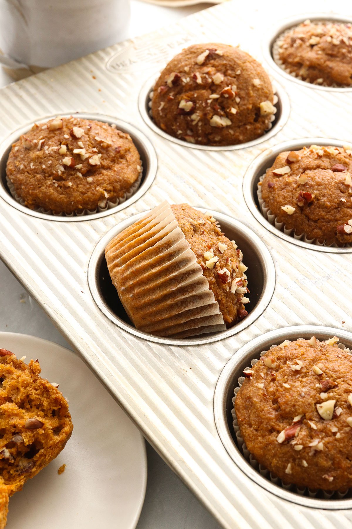 sweet potato muffins in their wrappers turned in a muffin pan.