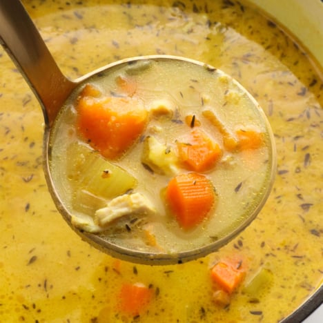 chicken turmeric soup lifted up on a ladle.