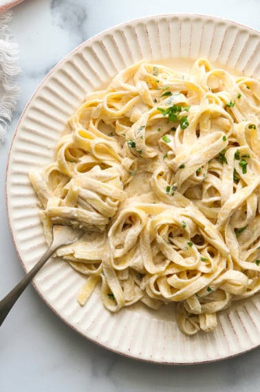 vegan alfredo sauce over noodles and twirled on a fork.