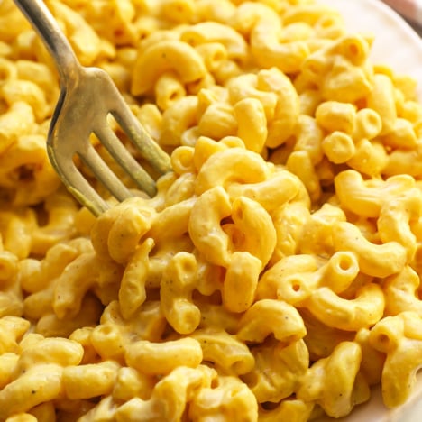 vegan mac and cheese served on a white plate with a fork.