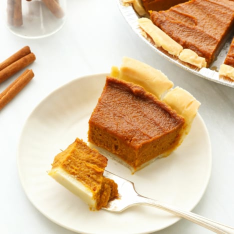 Vegan Pumpkin pie slice cut with a fork on a white plate.