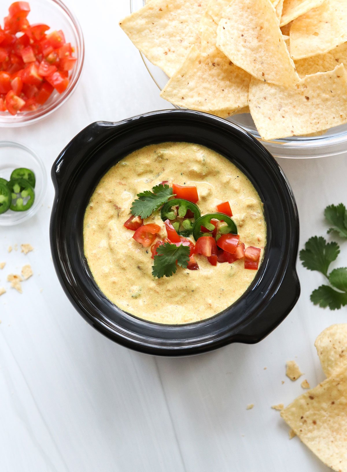 vegan cheese sauce in mini crockpot with tomatoes and jalapenos on top.