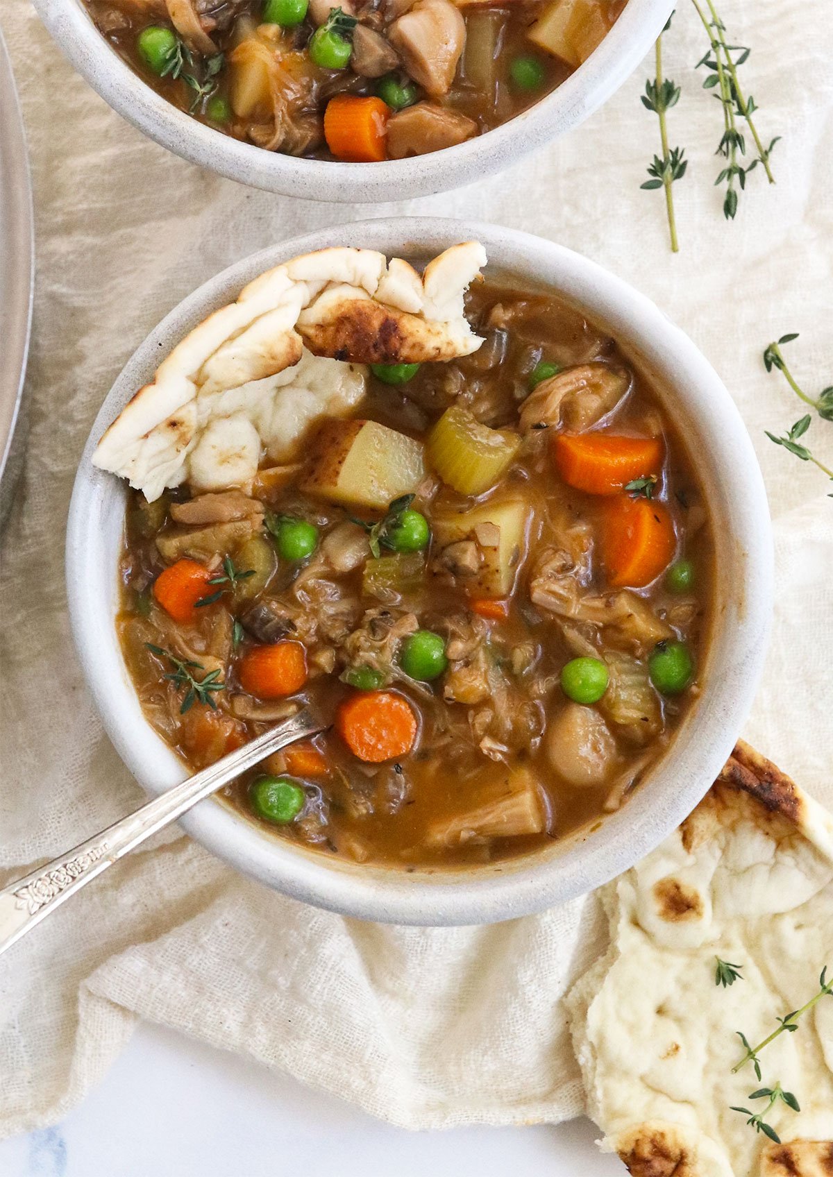 bowl of vegan stew served in a white bowl with naan bread.