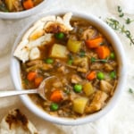 vegetable stew with a spoon and bread inside the bowl.