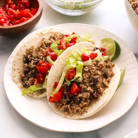 vegan tacos served with lettuce and tomato on a plate.