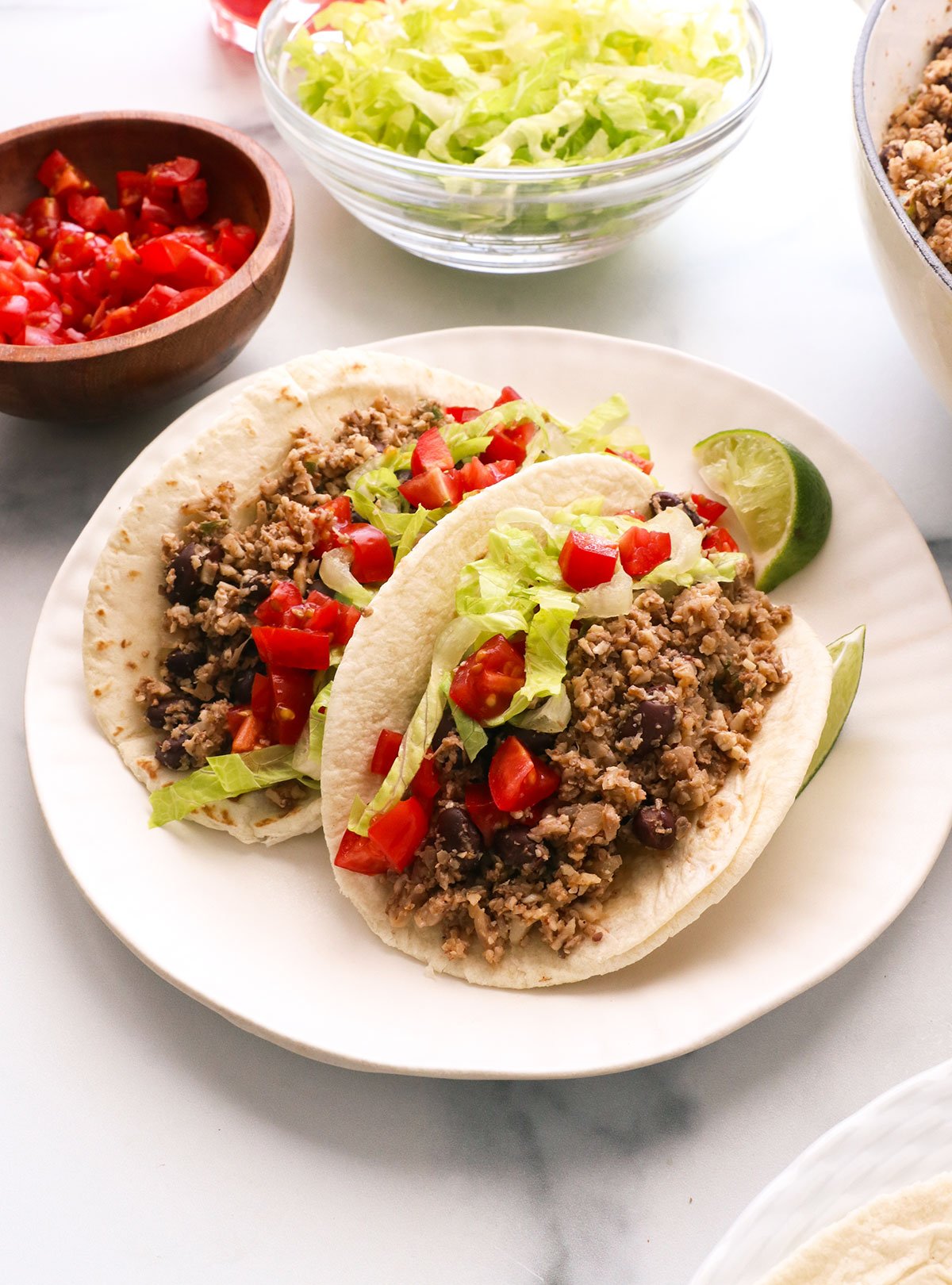 vegan tacos served with lettuce and tomato on a plate.