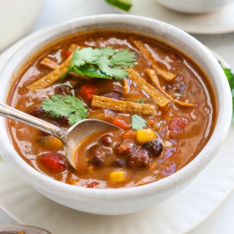 tortilla soup lifted from the bowl on a spoon.