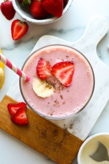 yogurt smoothie in a glass topped with banana and strawberries.