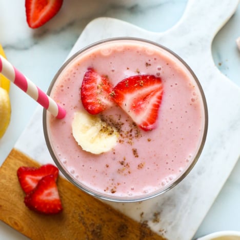 yogurt smoothie in a glass topped with banana and strawberries.