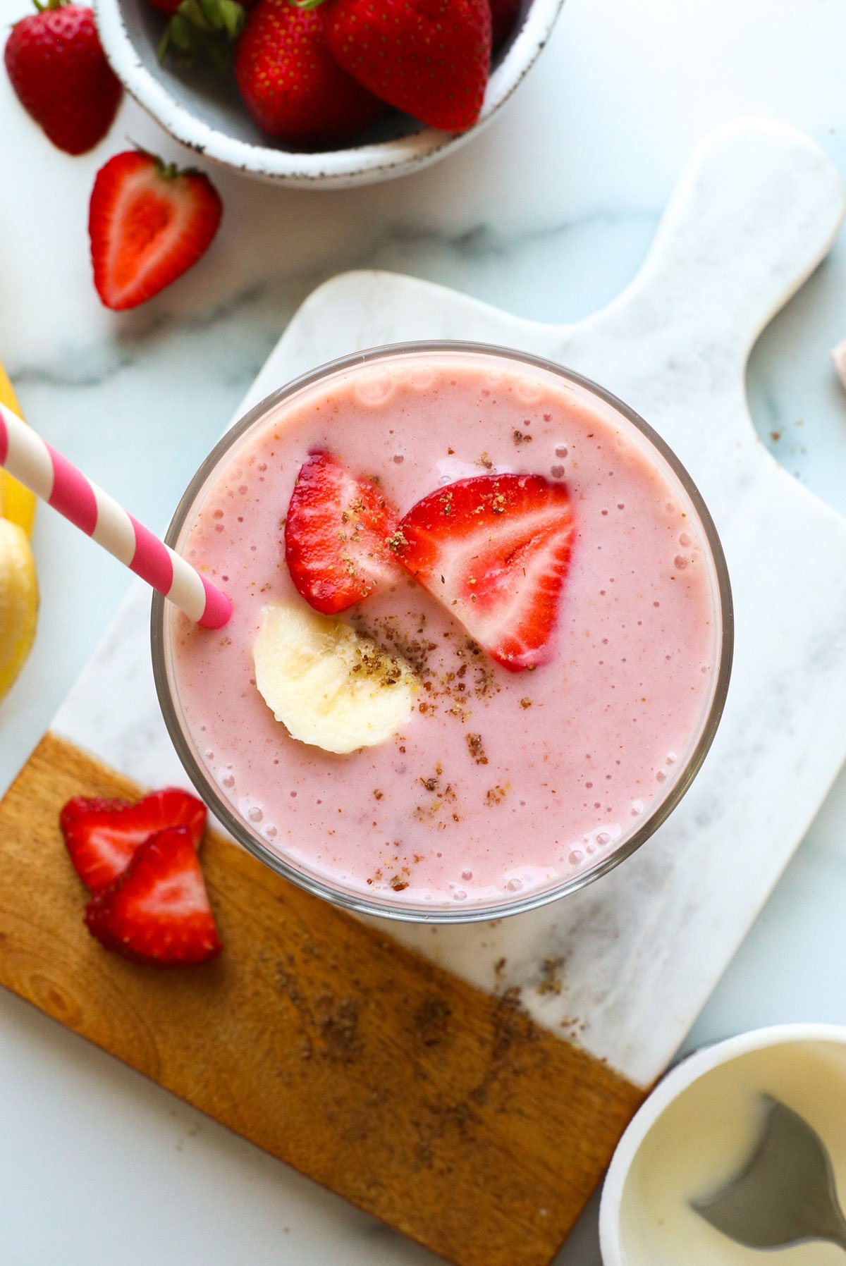 yogurt smoothie in a glass topped with banana and strawberries.